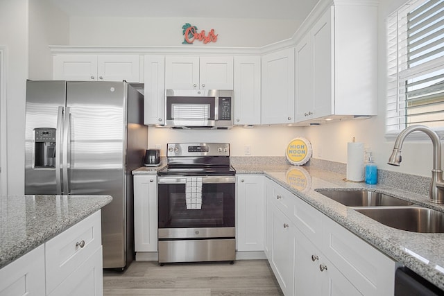 kitchen featuring sink, light stone countertops, white cabinets, and appliances with stainless steel finishes