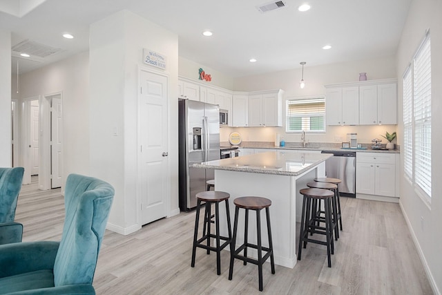 kitchen featuring stainless steel appliances, a center island, light hardwood / wood-style flooring, and pendant lighting