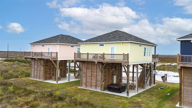 back of house with a patio area, a lawn, and a deck with water view