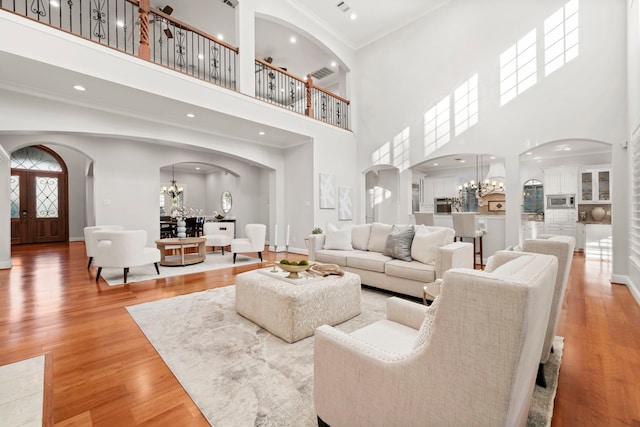 living room featuring french doors, ornamental molding, hardwood / wood-style flooring, an inviting chandelier, and a high ceiling