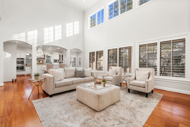 living room featuring hardwood / wood-style floors, a notable chandelier, a towering ceiling, and ornamental molding