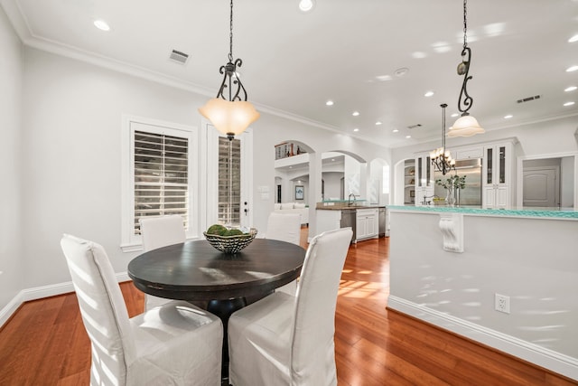 dining room featuring wood-type flooring, ornamental molding, and sink