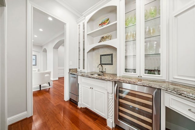 bar featuring wine cooler, light stone countertops, sink, and white cabinets