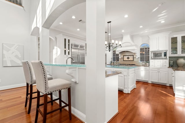 kitchen featuring built in appliances, white cabinetry, and decorative backsplash