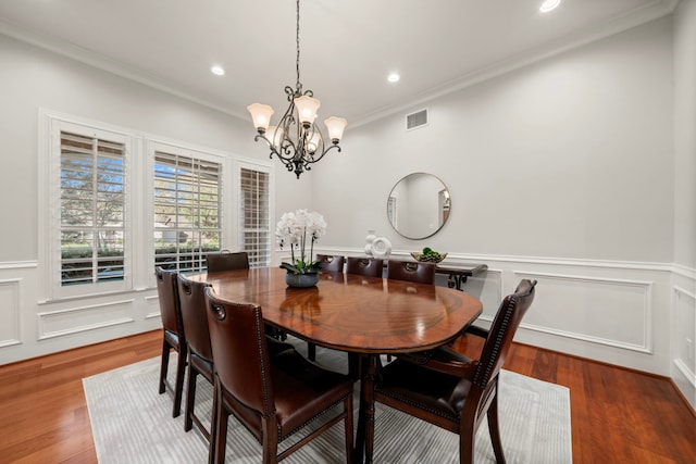 dining area featuring hardwood / wood-style flooring, an inviting chandelier, and ornamental molding