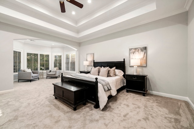 carpeted bedroom with a raised ceiling, ceiling fan, and ornamental molding