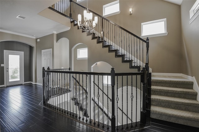 stairs featuring hardwood / wood-style flooring, ornamental molding, and an inviting chandelier