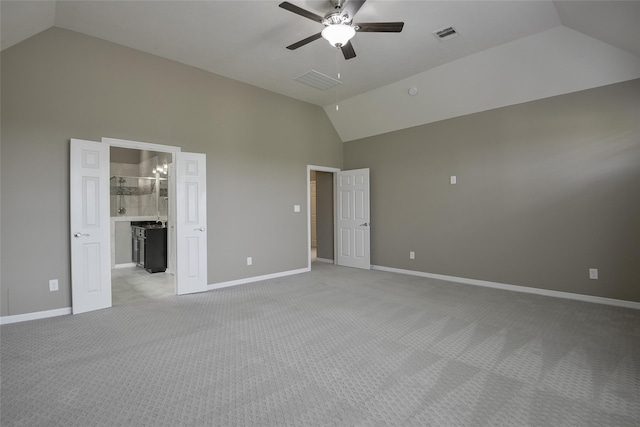 unfurnished bedroom featuring ensuite bath, ceiling fan, high vaulted ceiling, and light carpet