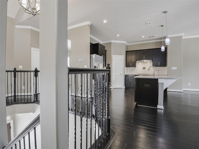 kitchen with stainless steel refrigerator, an inviting chandelier, dark hardwood / wood-style floors, an island with sink, and a breakfast bar