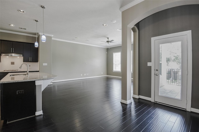 kitchen featuring decorative backsplash, dark hardwood / wood-style flooring, ceiling fan, a center island with sink, and hanging light fixtures