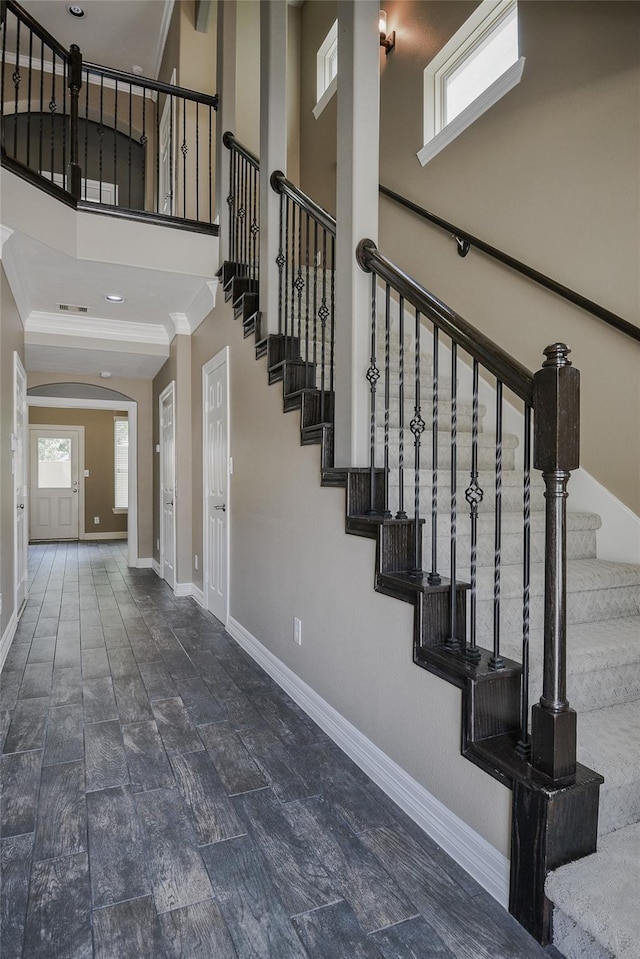 stairs featuring a towering ceiling and crown molding