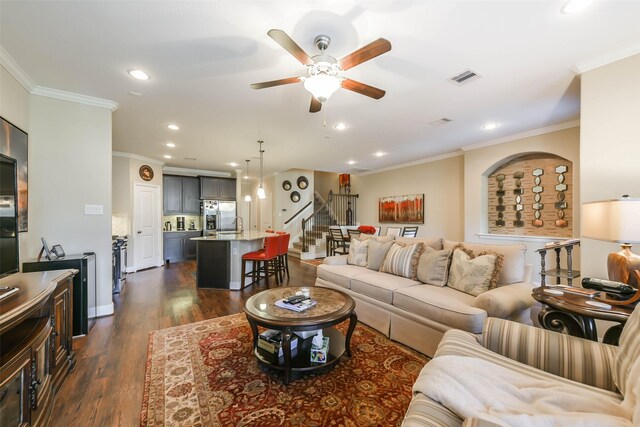 living room featuring dark hardwood / wood-style floors, ceiling fan, and crown molding