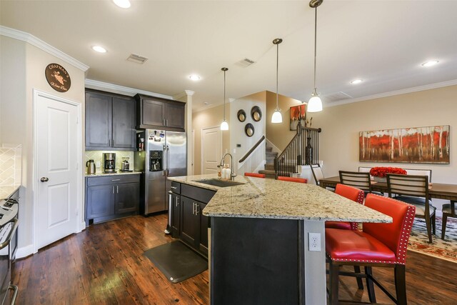 kitchen with sink, dark wood-type flooring, a kitchen breakfast bar, an island with sink, and appliances with stainless steel finishes