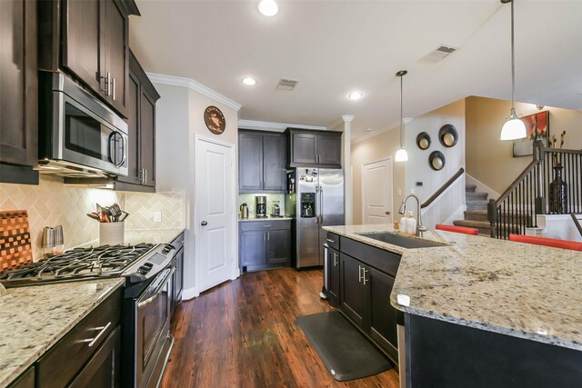 kitchen with sink, hanging light fixtures, dark hardwood / wood-style floors, decorative backsplash, and appliances with stainless steel finishes