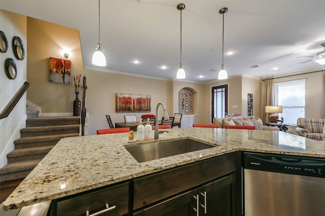 kitchen with light stone countertops, dishwasher, sink, decorative light fixtures, and ornamental molding