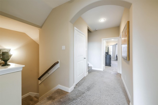 corridor featuring light colored carpet and vaulted ceiling