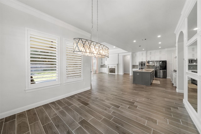 unfurnished living room with a notable chandelier, ornamental molding, and dark wood-type flooring