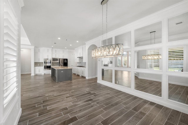 kitchen featuring white cabinets, pendant lighting, a kitchen island with sink, and sink