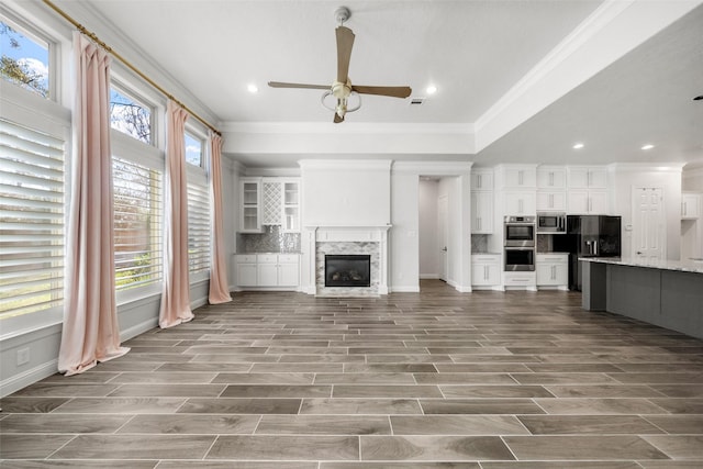 unfurnished living room with hardwood / wood-style floors, ceiling fan, ornamental molding, and a premium fireplace