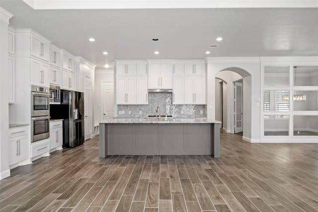 kitchen with crown molding, white cabinets, a kitchen island with sink, and appliances with stainless steel finishes