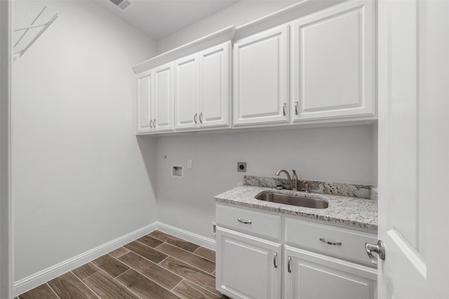 washroom featuring electric dryer hookup, hookup for a washing machine, sink, and cabinets