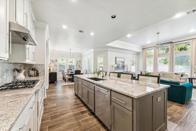 kitchen featuring white cabinets, sink, hanging light fixtures, an island with sink, and stainless steel appliances