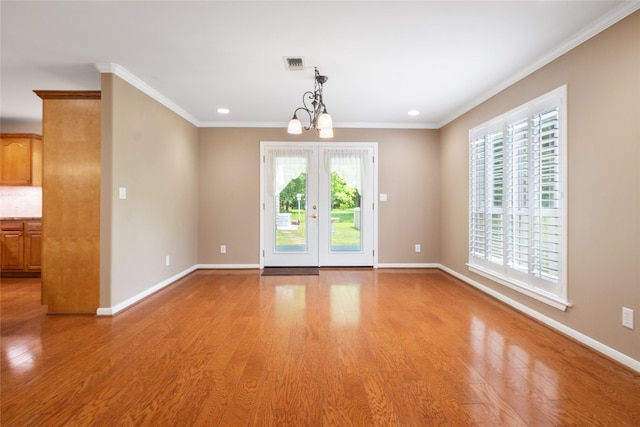 unfurnished room with crown molding, french doors, light wood-type flooring, and an inviting chandelier