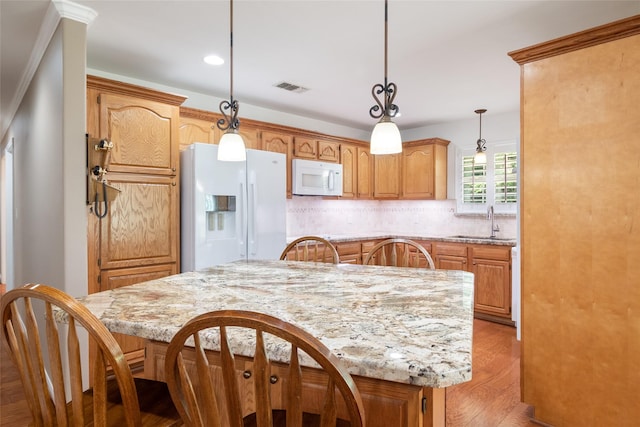 kitchen with a center island, sink, light stone counters, and white appliances