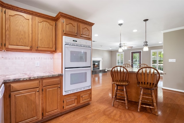 kitchen featuring pendant lighting, white appliances, light stone counters, tasteful backsplash, and ornamental molding