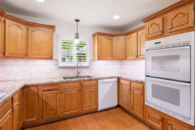 kitchen featuring light stone countertops, white appliances, light hardwood / wood-style flooring, and sink