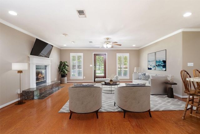 living room with hardwood / wood-style flooring, ceiling fan, ornamental molding, and a premium fireplace