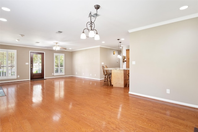 unfurnished living room featuring crown molding, ceiling fan with notable chandelier, and light hardwood / wood-style floors