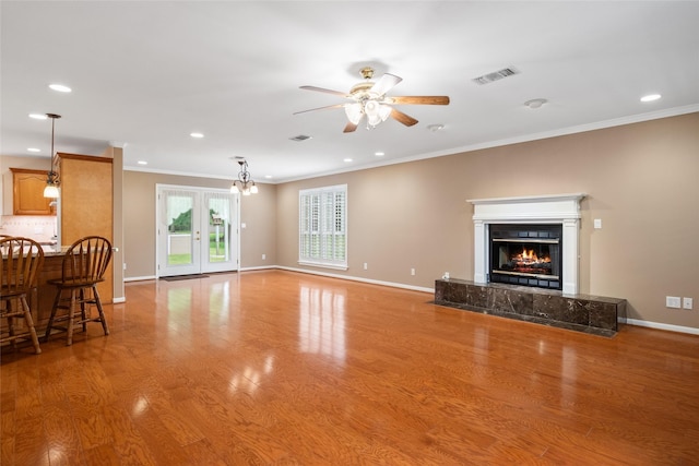 living room with ceiling fan, ornamental molding, a tiled fireplace, and light hardwood / wood-style floors