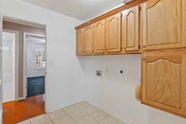 clothes washing area featuring electric dryer hookup, cabinets, light tile patterned floors, and hookup for a washing machine