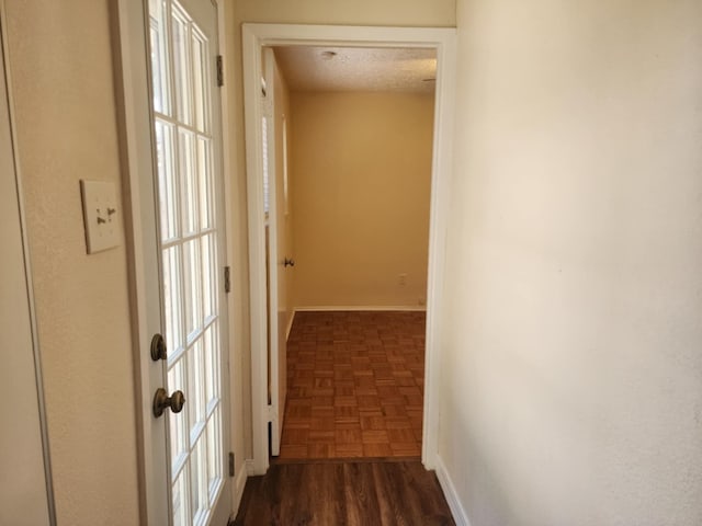 hallway featuring dark parquet floors and a textured ceiling