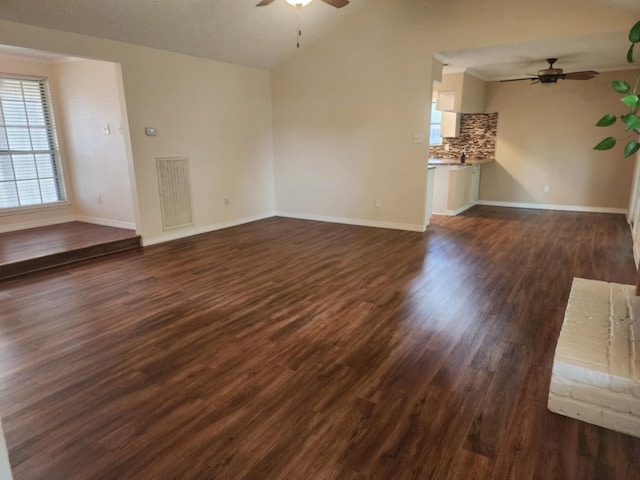 unfurnished living room with a textured ceiling, dark hardwood / wood-style flooring, vaulted ceiling, and ceiling fan