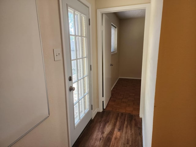 doorway to outside featuring dark parquet flooring, a wealth of natural light, and a textured ceiling