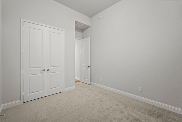 unfurnished bedroom with light carpet and a closet