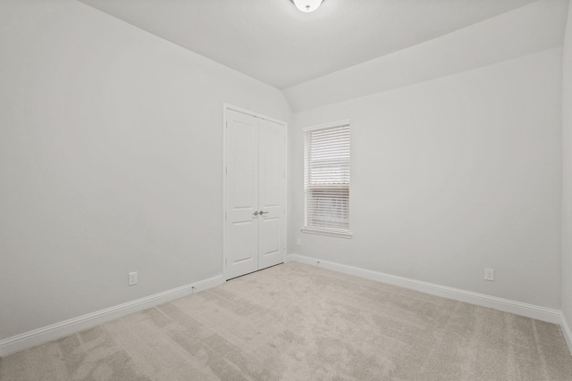 spare room featuring light colored carpet and vaulted ceiling