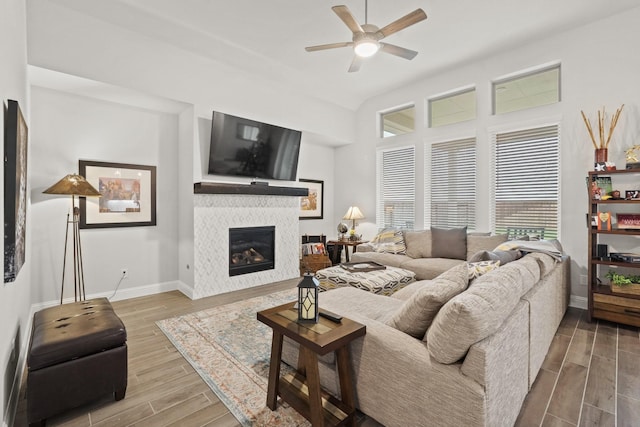 living room with a tile fireplace and ceiling fan