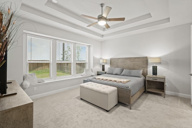 bedroom featuring light carpet, a raised ceiling, and ceiling fan