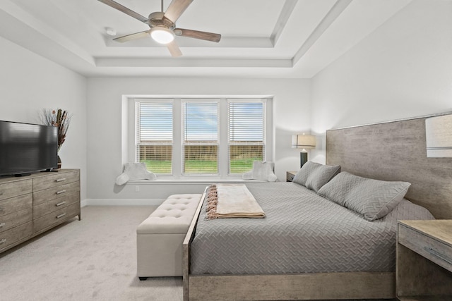 carpeted bedroom with a raised ceiling and ceiling fan