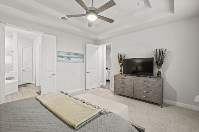 carpeted bedroom with connected bathroom, a raised ceiling, and ceiling fan