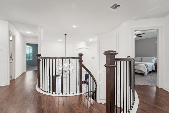 corridor with dark hardwood / wood-style floors and an inviting chandelier