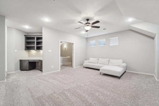 carpeted living room with built in desk, vaulted ceiling, and ceiling fan