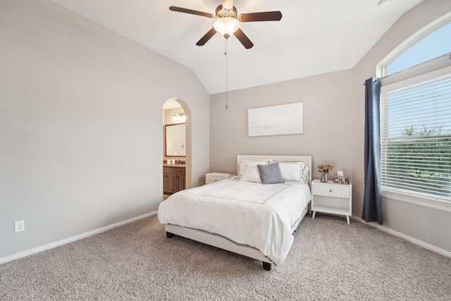 bedroom featuring ceiling fan, lofted ceiling, connected bathroom, and multiple windows