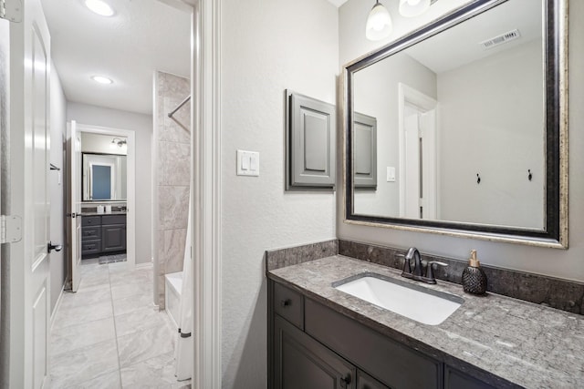 bathroom featuring vanity and tiled shower / bath