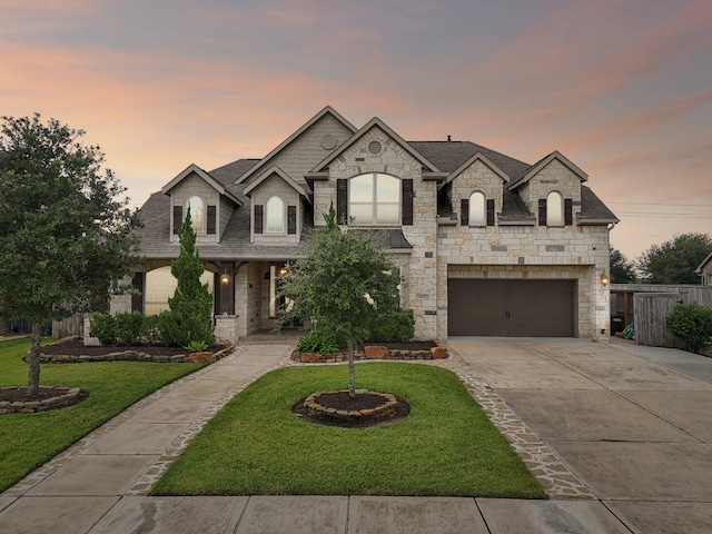 french country style house featuring a garage and a lawn