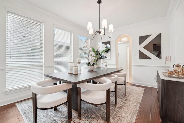 dining area with ornamental molding, dark wood-type flooring, and a chandelier