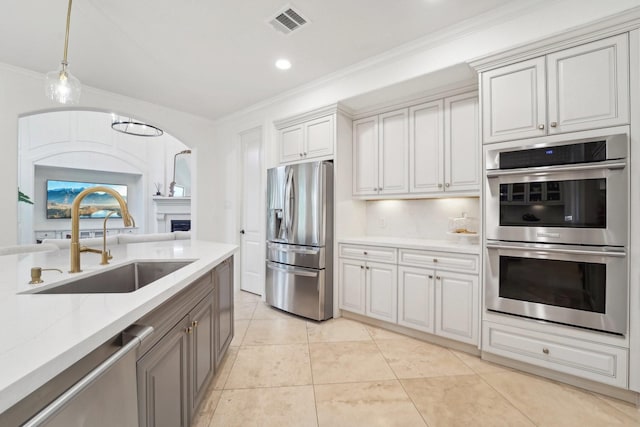 kitchen featuring sink, crown molding, decorative light fixtures, white cabinets, and appliances with stainless steel finishes